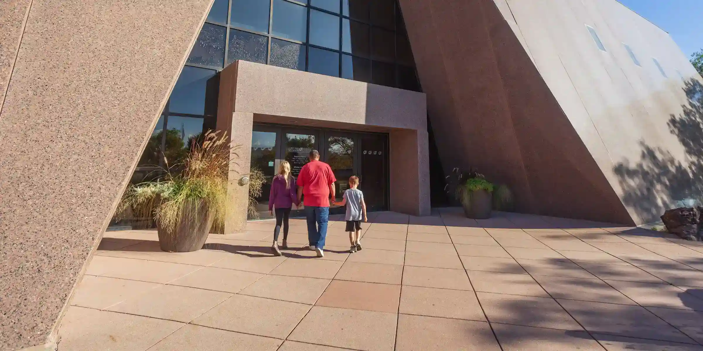 man takes two kids into the front of the Journey Museum